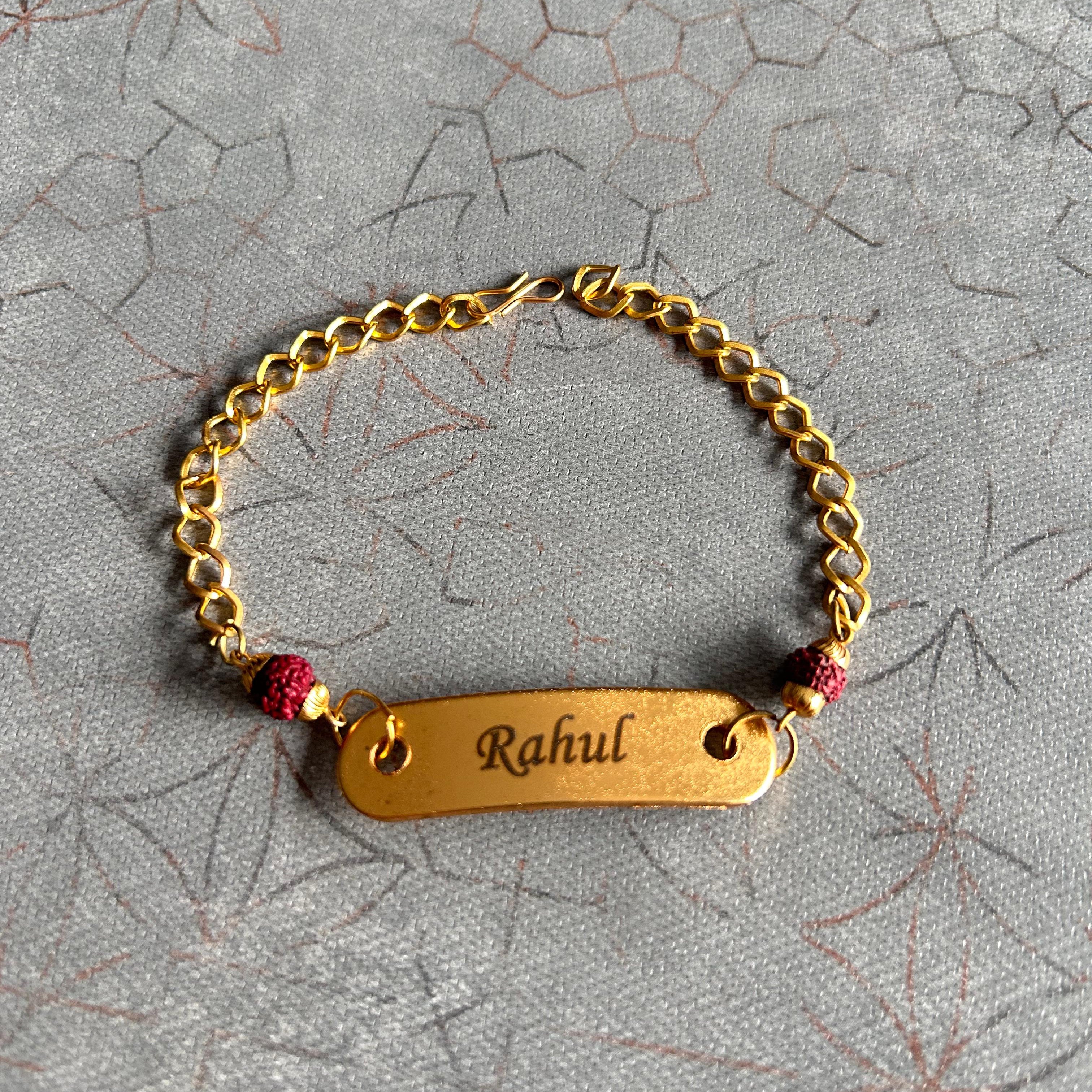 Gold bracelet with a name tag 'Rahul' on a textured gray background - The Gifting Era