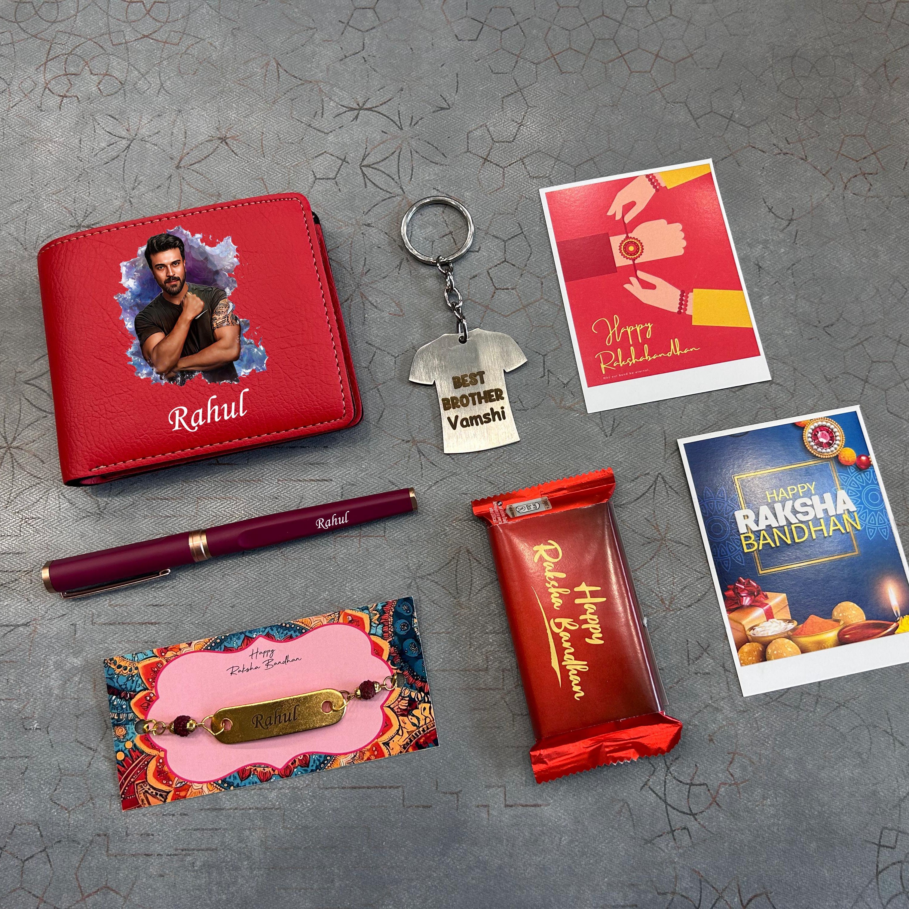 Collection of Raksha Bandhan-themed items including a red wallet, keychain, pen, card, and chocolate bar on a textured gray surface. - The Gifting Era