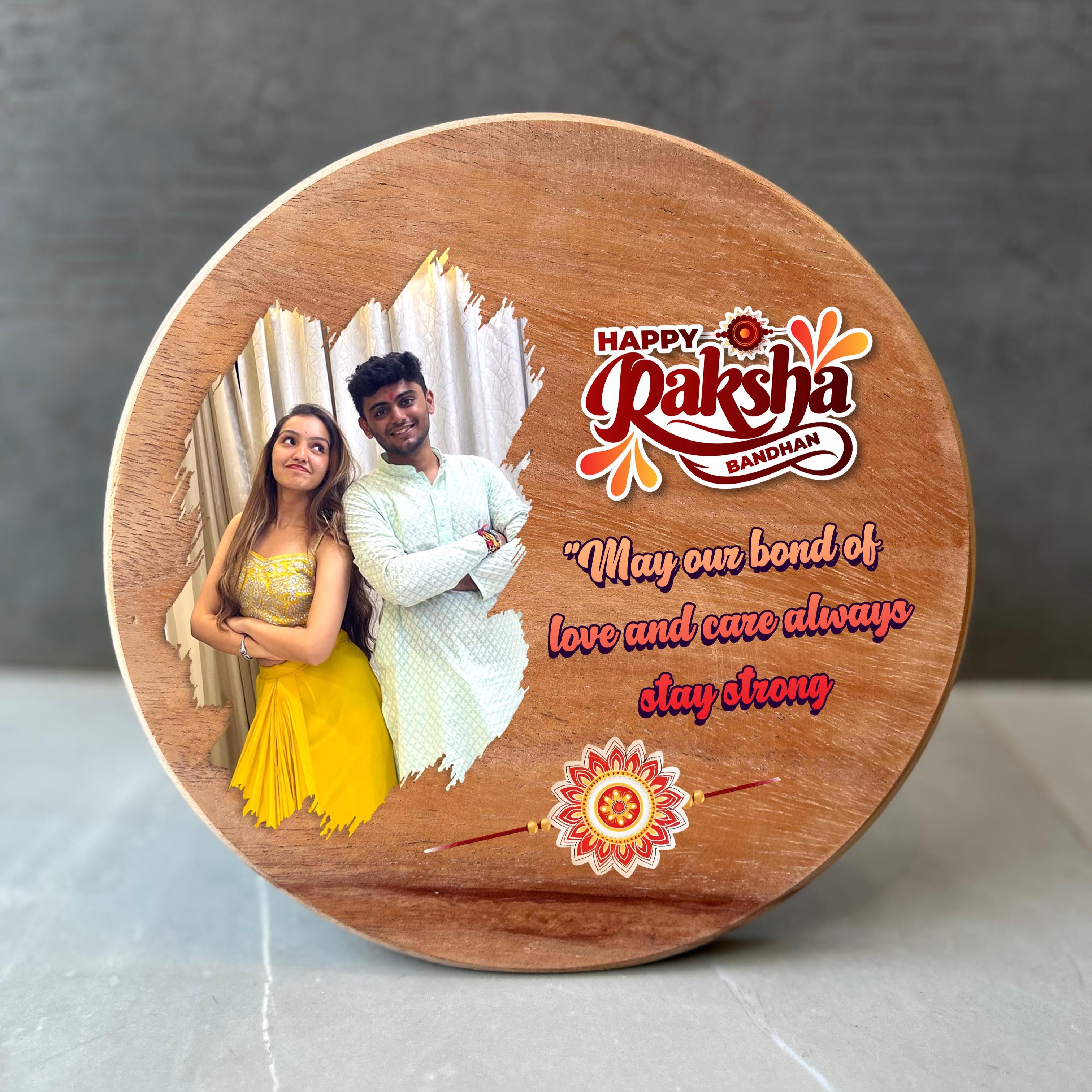 Round wooden plaque with a photo of a couple and 'Happy Raksha Bandhan' text on a gray background. - The Gifting Era