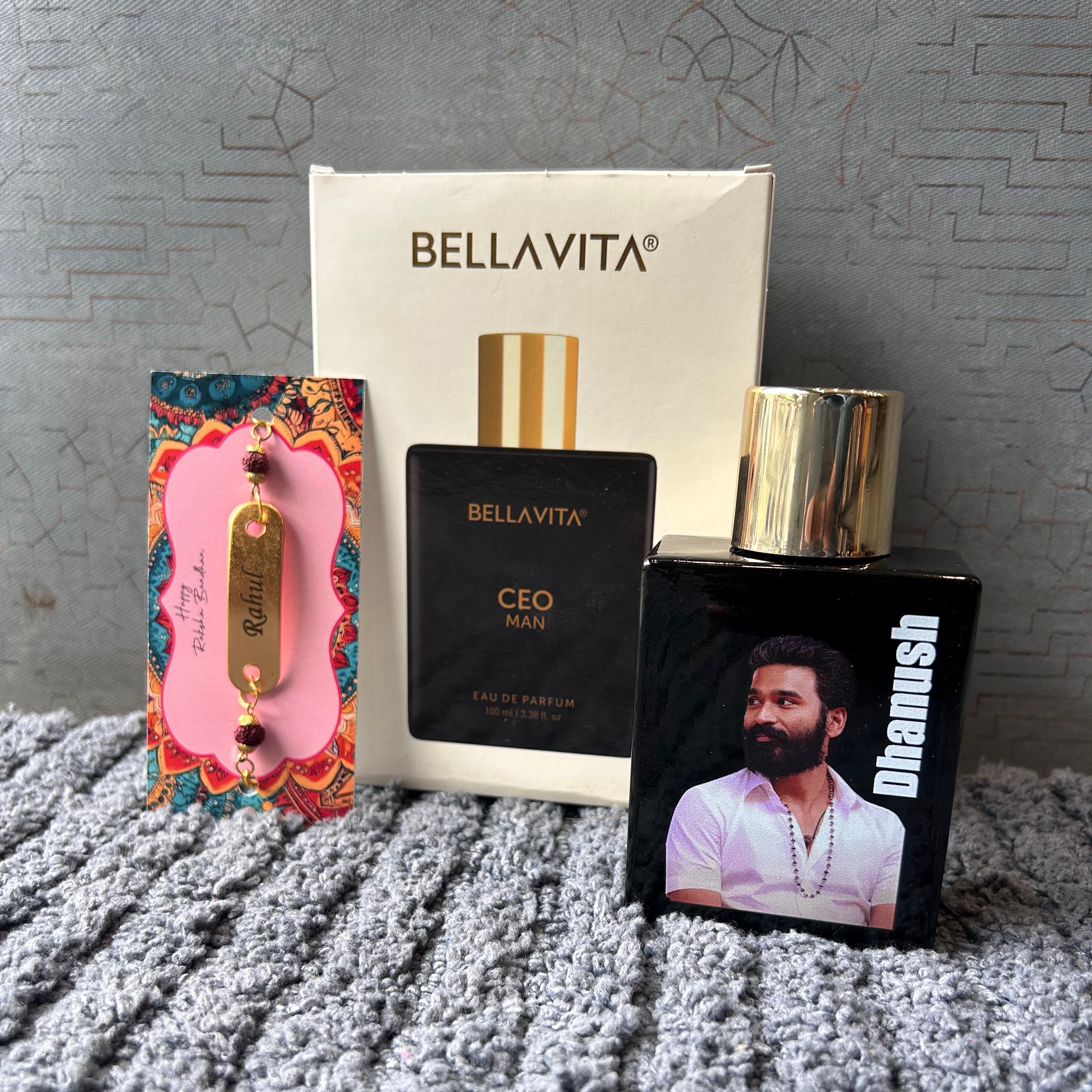 Three items including a Bellavita box, a Bellavita perfume bottle, and a Dhanush product on a textured surface. - The Gifting Era