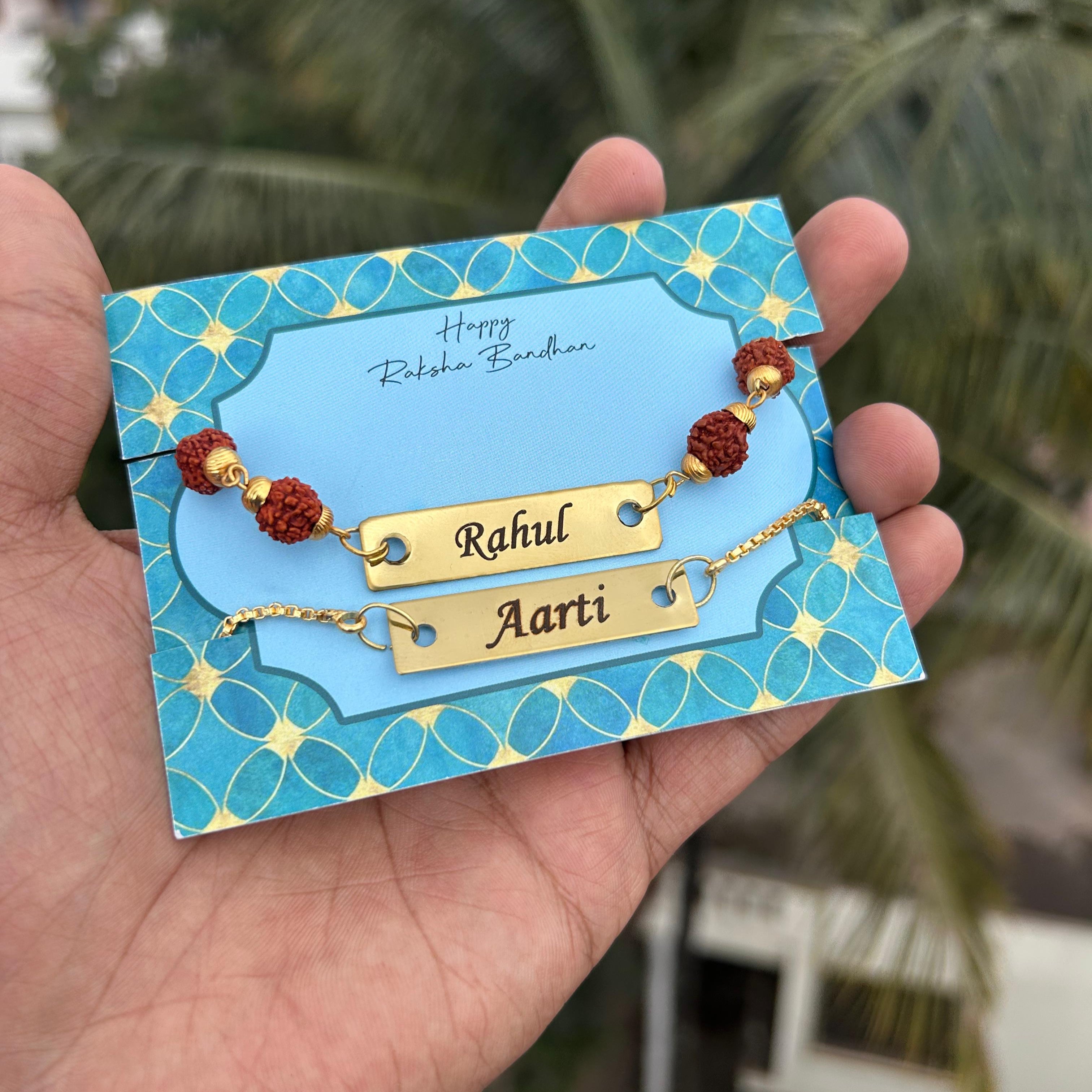 Hand holding a card with gold nameplates 'Rahul' and 'Aarti' on a blue background. - The Gifting Era