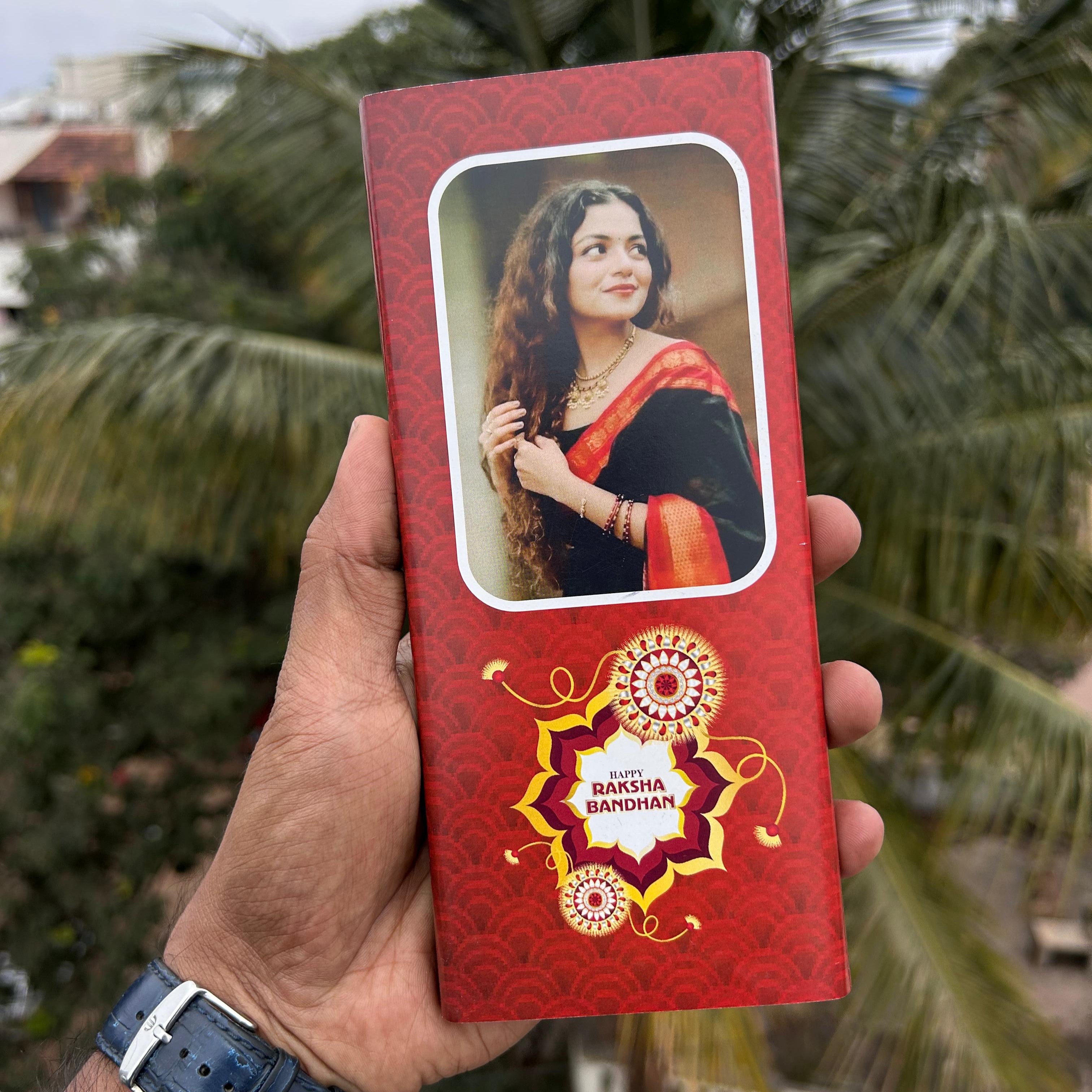Red box with a portrait of a woman on it, held outdoors with greenery in the background - The Gifting Era