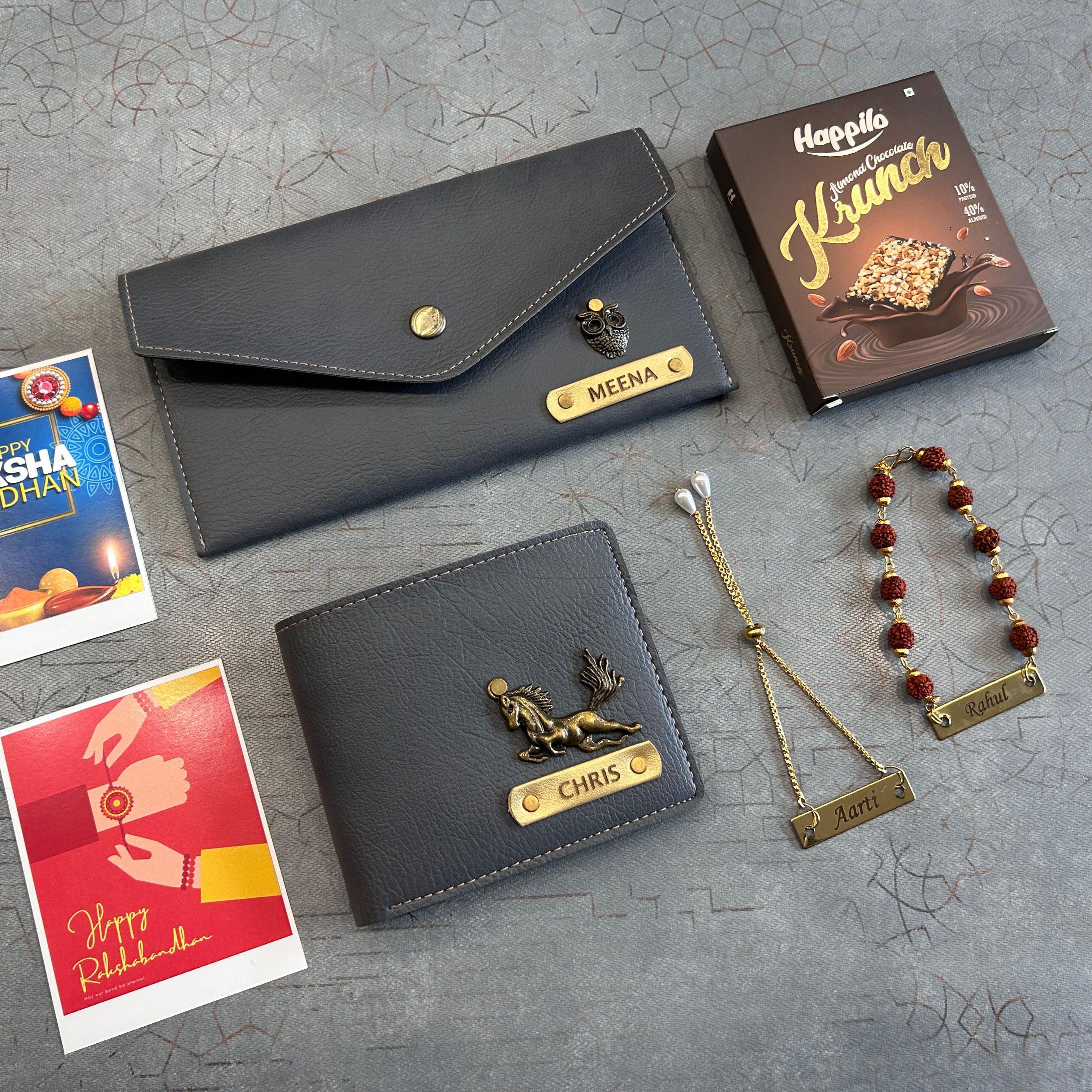 Two black wallets with gold accents, a necklace, and two cards on a gray textured surface. - The Gifting Era