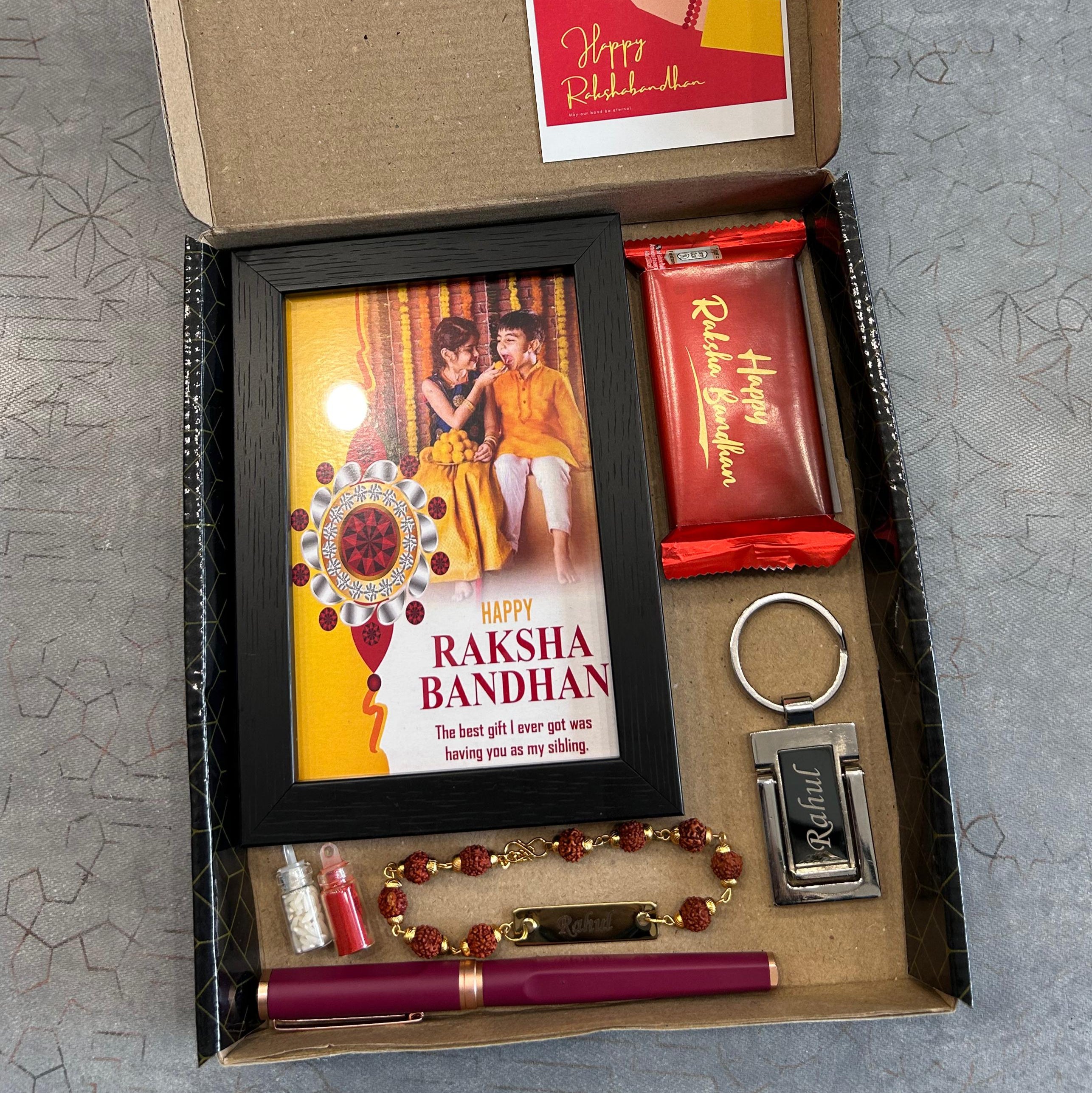 Gift box with Raksha Bandhan-themed items including a photo frame, chocolate, and keychain. - The Gifting Era