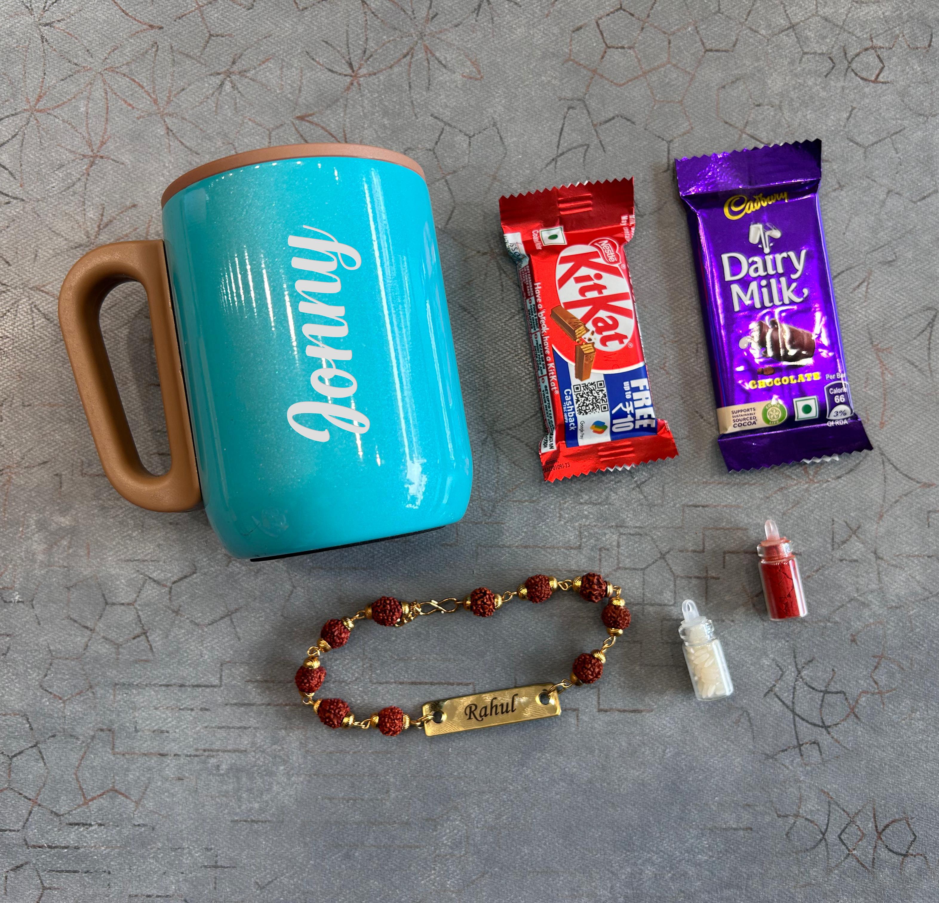 Turquoise mug with 'Donny' branding, KitKat and Dairy Milk chocolate bars, a bracelet, and a small bottle on a textured gray surface. - The Gifting Era