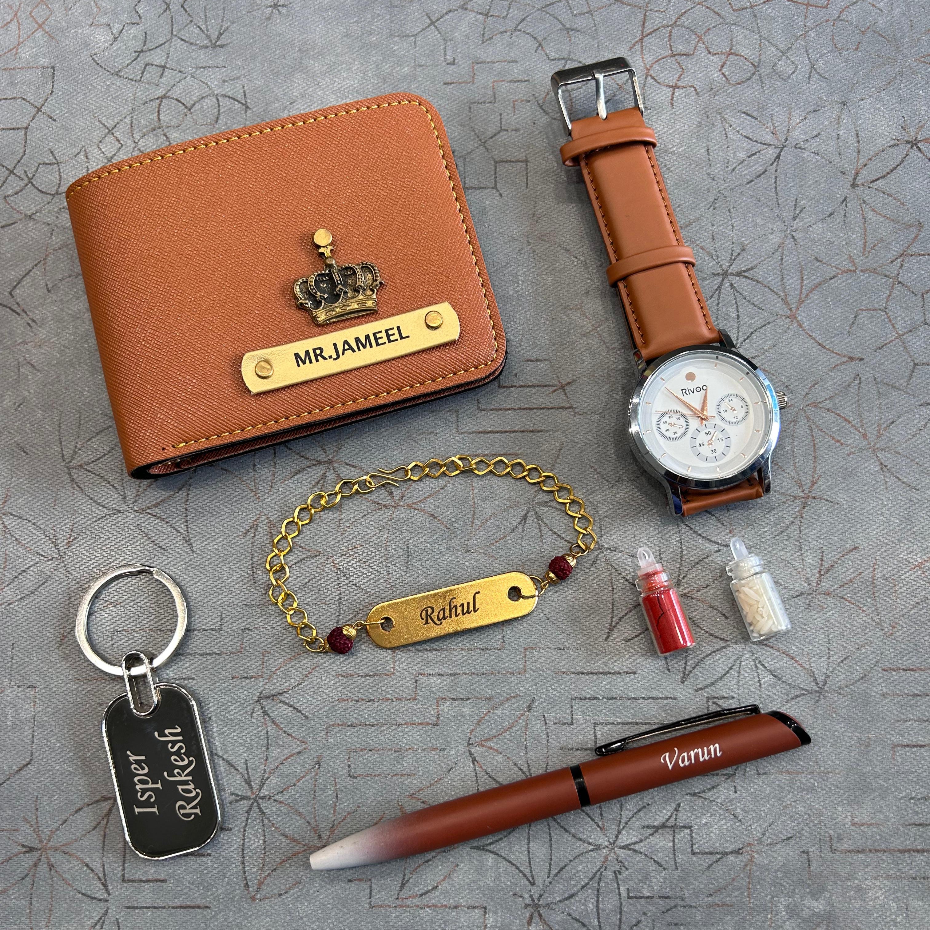 Collection of personalized accessories including a wallet, watch, keychain, bracelet, and pen on a textured surface.  The Gifting Era