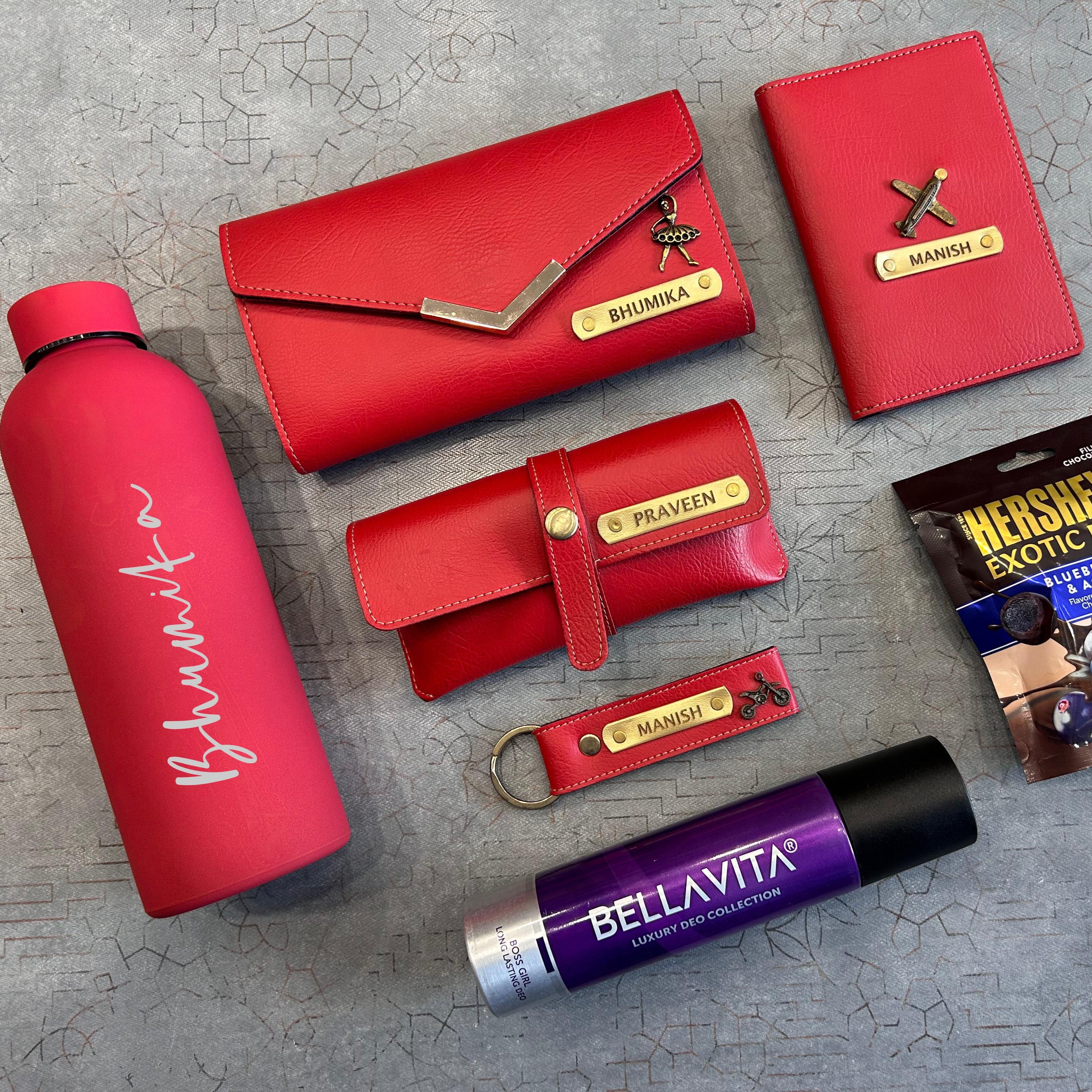 Collection of red and purple products including a water bottle, wallet, and lip balm on a textured surface. - The Gifting Era