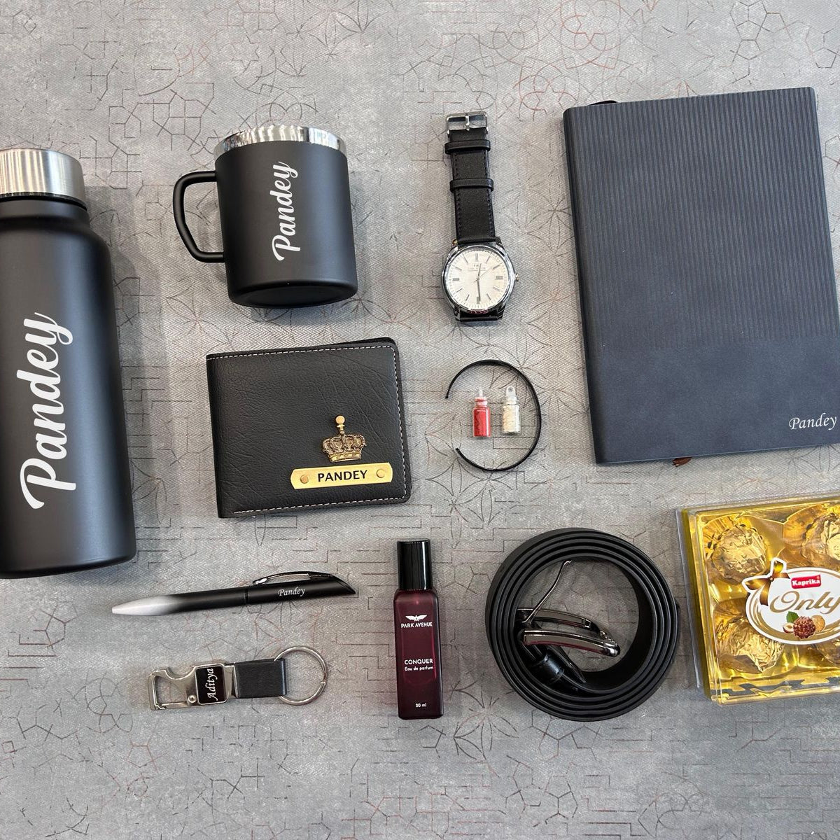 Collection of branded items including a water bottle, mug, watch, wallet, and others on a textured surface. - The Gifting Era