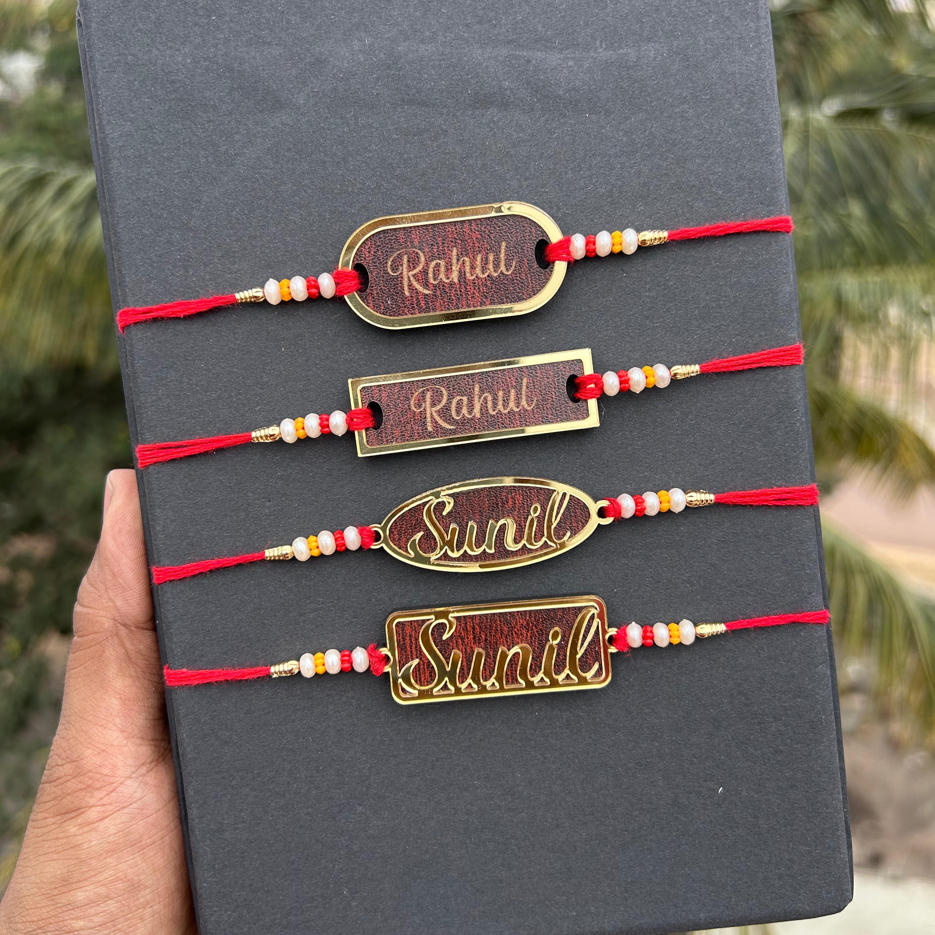 Three gold bracelets with red strings on a black box, held by a hand with a blurred green background. - The Gifting Era