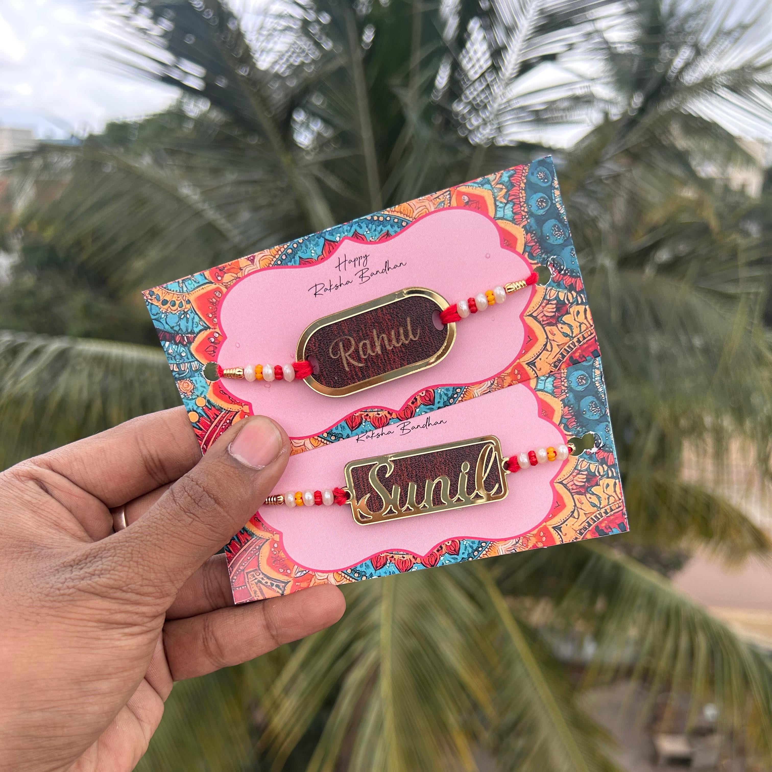 Colorful card with two bracelets held by a hand, palm trees in the background - The Gifting Era