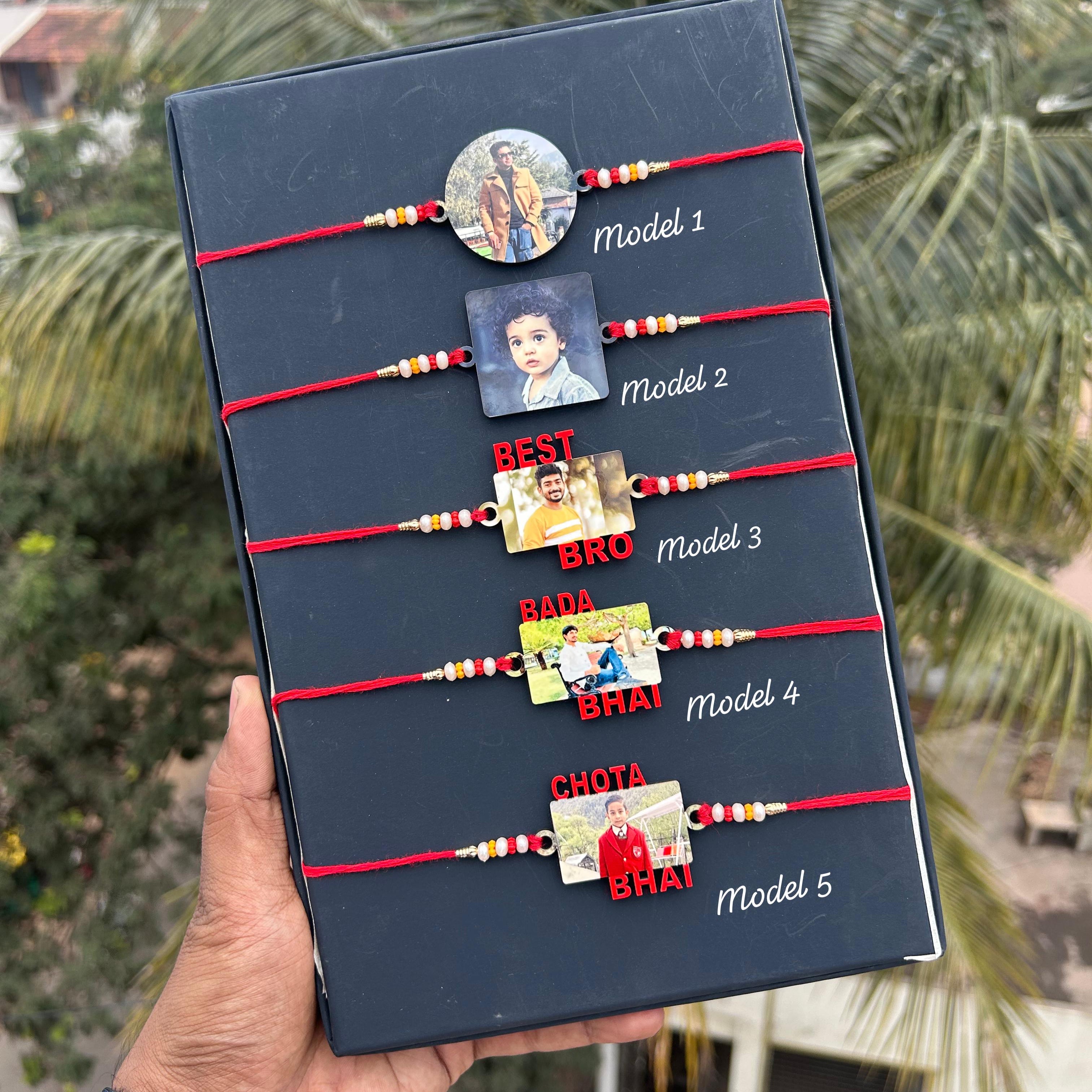 Set of five Rakhi (brother's bracelet) with cards on a display board held by a hand, with a blurred outdoor background. - The Gifting Era