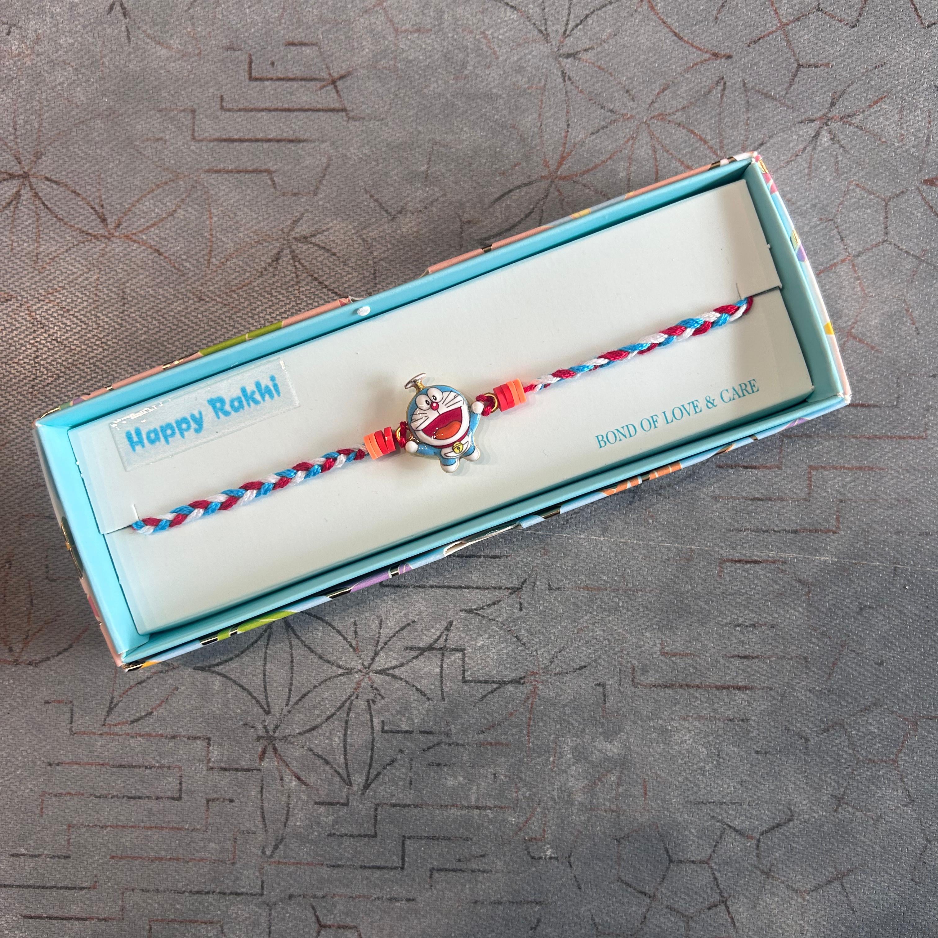 Bracelet with turtle charm in a box labeled 'Happy Rakhi' on a textured surface - The Gifting Era