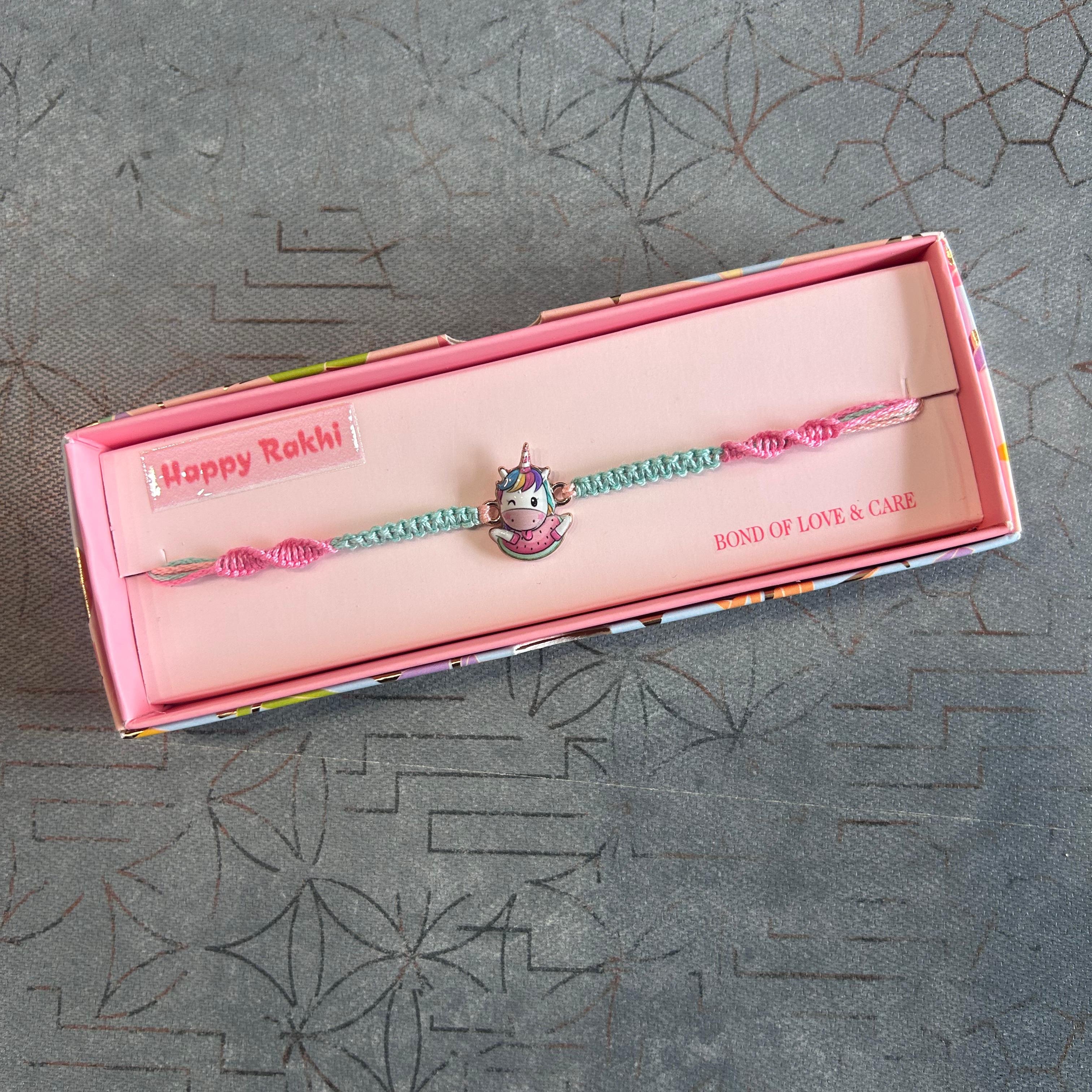 Bracelet with a unicorn charm in a pink box on a textured gray surface - The Gifting Era