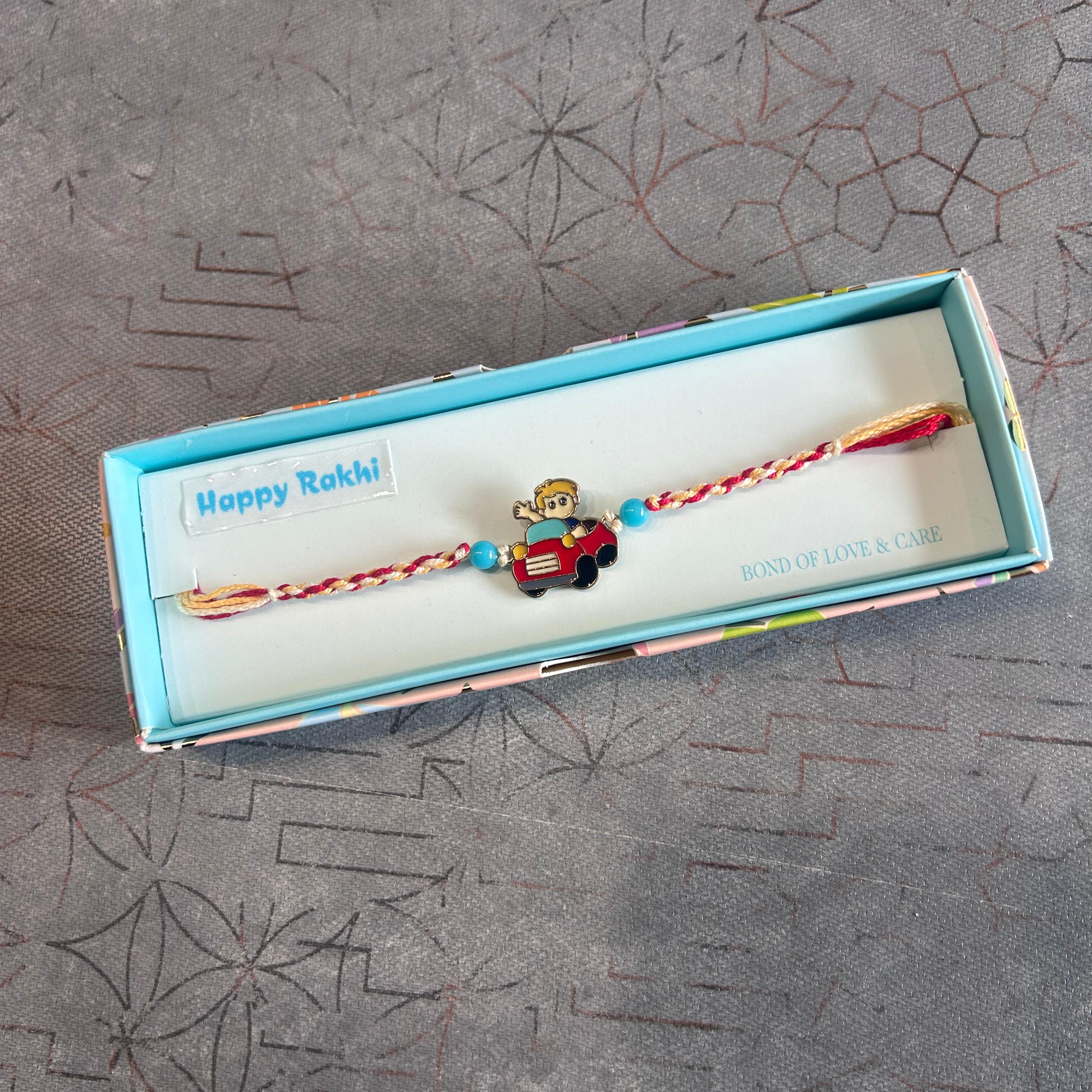 Rakhi with a toy car design in a box on a textured surface - The Gifting Era