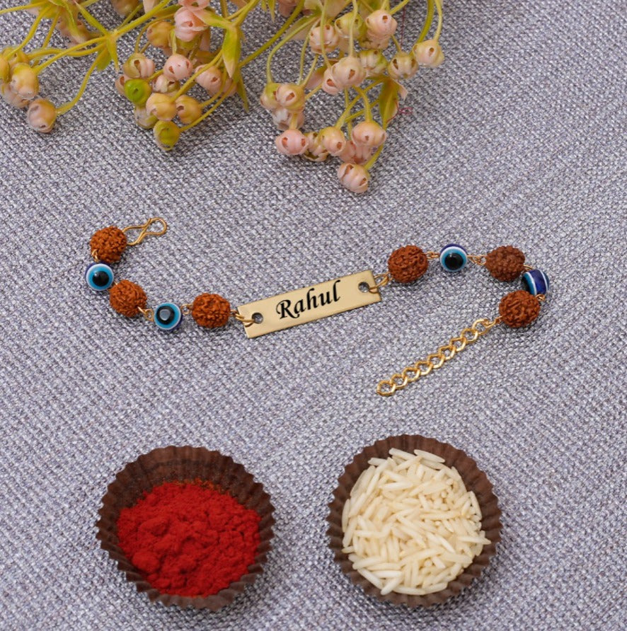 Bracelet with 'Rahul' tag and decorative elements on a textured surface with small containers of red and white powders. - The Gifting Era