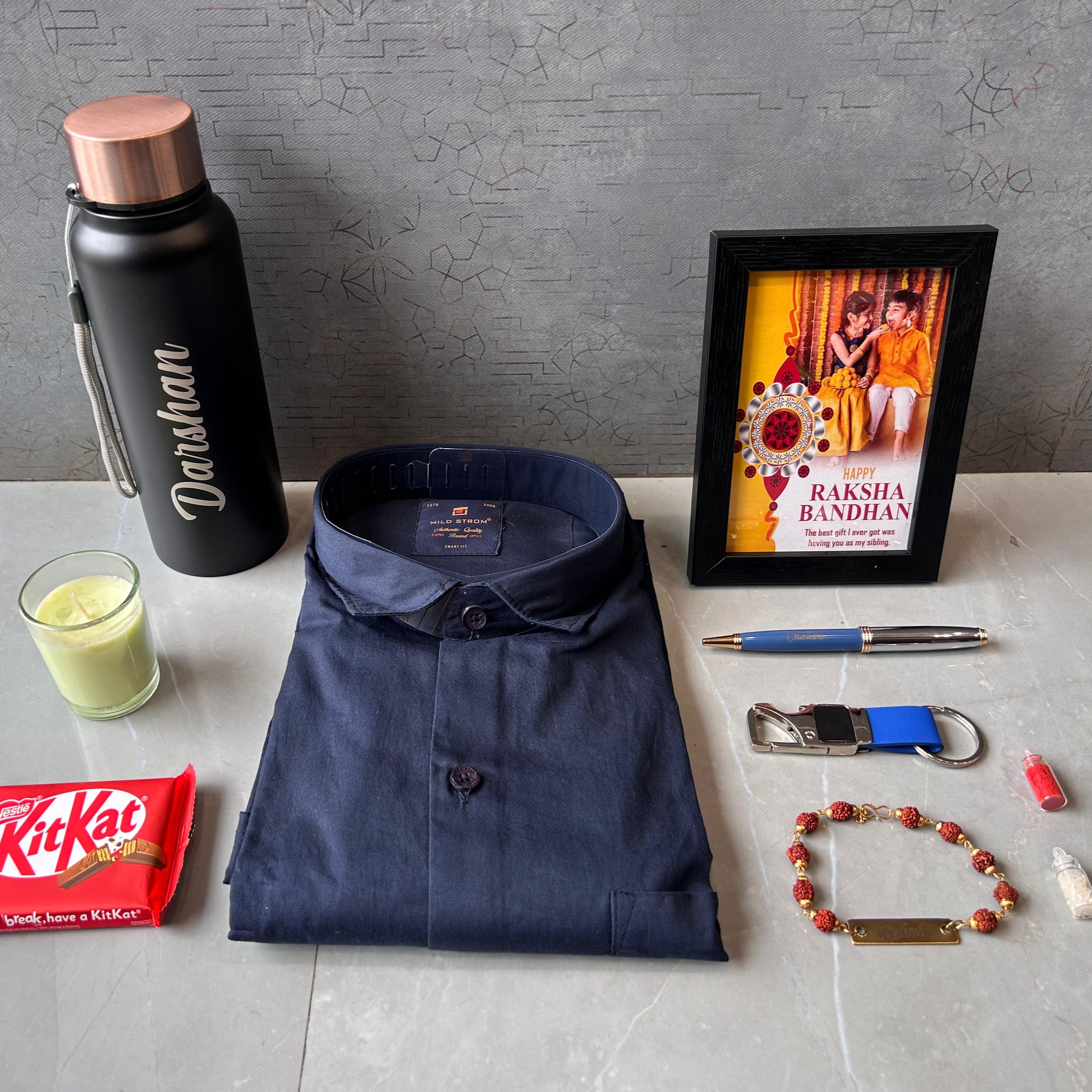 Collection of items including a navy shirt, Darshan bottle, KitKat bar, glass with green liquid, photo frame, pen, and other small objects on a gray surface. - The Gifting Era