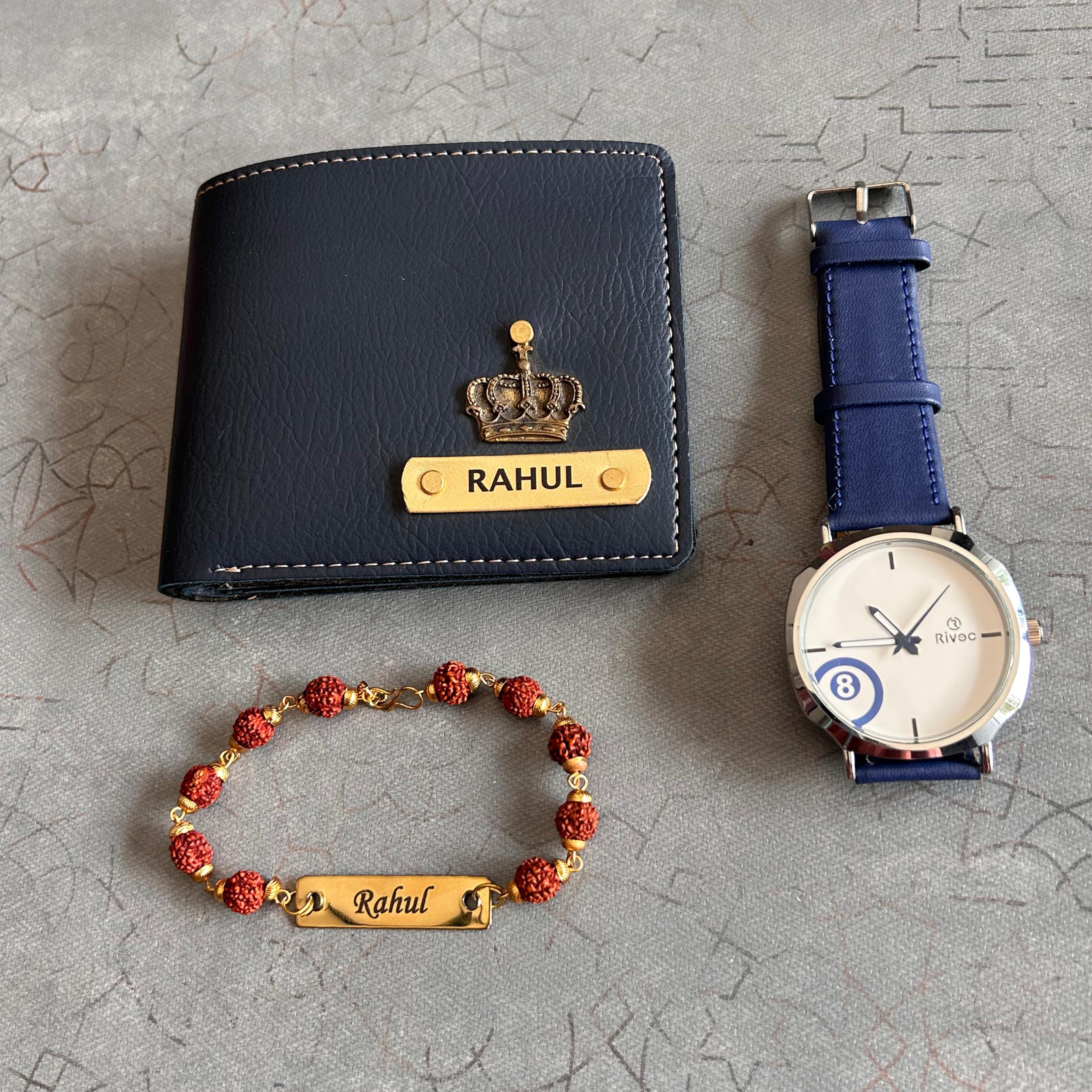 Black wallet, blue watch, and red bracelet with 'Rahul' engraving on a textured gray surface